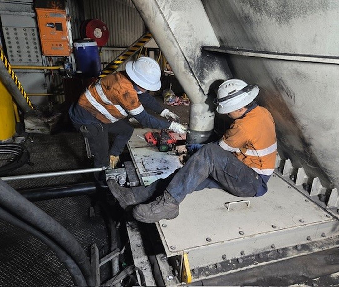 Two R8D crew members wearing PPE working on mining plant equipment