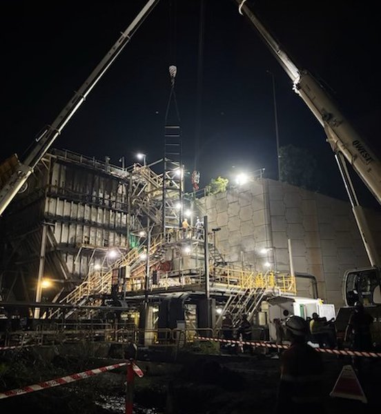 Twin cranes lifting at night during a chain feeder change-out